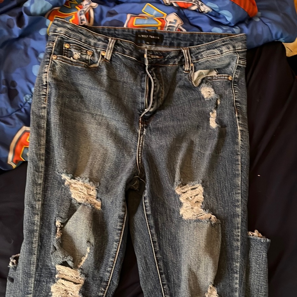 Darker blue jeans with rips around the ankles and all down the legs